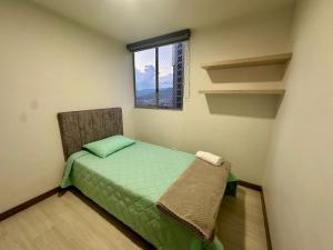 una piccola camera da letto con un letto verde e una finestra di Moderno Apartamento Sabaneta- Century Tower II a Envigado Altre 74 foto