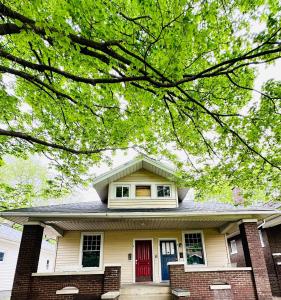 ein Haus mit einer roten Tür und einem Baum in der Unterkunft House of Color EVV Stylish Apartments in Evansville