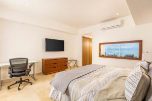 a bedroom with a bed and a desk and a television at Wake Up to Paradise – Stunning 2BR Condo Right on the Beach in Puerto Vallarta +56 photos