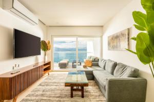 a living room with a couch and a tv at Wake Up to Paradise – Stunning 2BR Condo Right on the Beach in Puerto Vallarta
