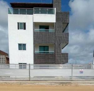 a tall brick building with a fence in front of it at Flat - Jacumã - Conde in Conde
