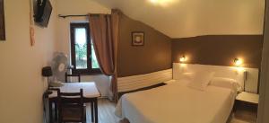 a bedroom with a bed and a table and a window at Auberge Les Glycines in Cancon