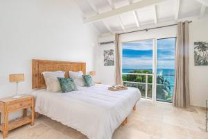 a bedroom with a bed with a view of the ocean at La Sirene du Diamant, villa de luxe sur la plage,18 personnes in Le Diamant +83 photos