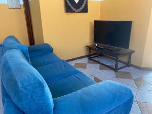 a blue couch in a living room with a tv at Imana Hostel in Florianópolis