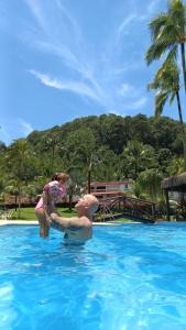 una ragazza e un uomo in acqua in piscina di Casa inteira na PRAIA & SERRA Melhor Resort Angra a Conquista