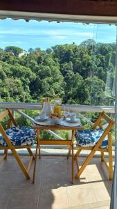 un tavolo e sedie su un balcone con vista di Casa inteira na PRAIA & SERRA Melhor Resort Angra a Conquista