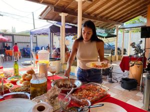 a woman holding a plate of food on a table at Imana Hostel in Florianópolis