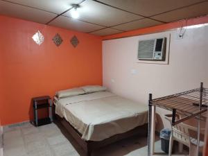ein Schlafzimmer mit zwei Betten und einer orangefarbenen Wand in der Unterkunft Departamento Doki in Hermosillo