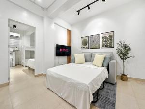 a white bedroom with a bed and a tv at Family Apartment By The Beach with Kitchen Netflix Station 3 Beachfront in Boracay