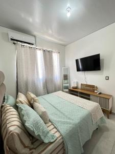 Un dormitorio con una cama con un televisor en la pared. en Casa Bonita, en San Miguel