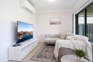 un soggiorno con TV e divano di Leppington 5Br house near train and shopping a Leppington