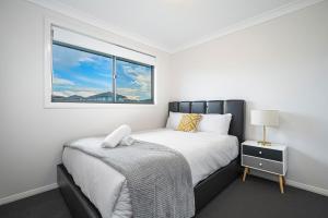 una camera da letto bianca con un letto e una finestra di Leppington 5Br house near train and shopping a Leppington