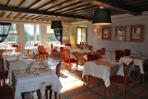 un restaurant avec des tables blanches, des chaises et des fenêtres dans l'établissement L'auberge Du Cochon D'or, à Beuzeville