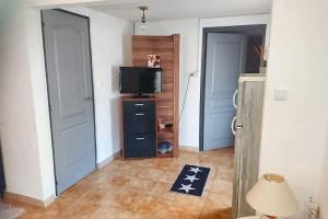 a room with a television and a hallway with two doors at Appartement accueillant à Penne-d'Agenais - 32 m² - Terrasse in Penne-dʼAgenais