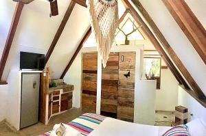 a attic room with a bed and a refrigerator at Kin Resort Lodge in Maya Beach