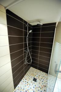 een douche in een badkamer met een betegelde muur bij Les Arcades in Limoux