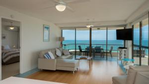 a living room with a couch and a room with a balcony at Norfolk Luxury Beachfront Apartments in Gold Coast