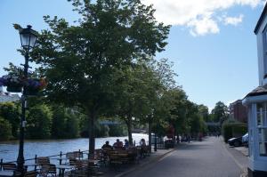 a group of people sitting on benches next to a river at No. 23 at The Moorings, Chester in Chester