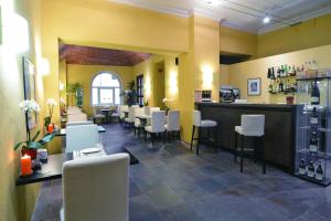 a restaurant with a bar with white chairs and tables at Hotel Boutique Antiche Mura in Saluzzo