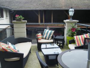 eine Terrasse mit Korbstühlen und Tischen auf einem Balkon in der Unterkunft Hôtel Gambetta in Lons-le-Saunier