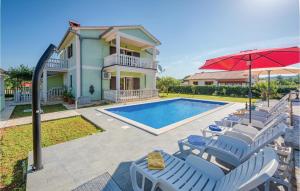 a house with a swimming pool with chairs and an umbrella at Stunning Home In Kapelica With Wifi in Raša