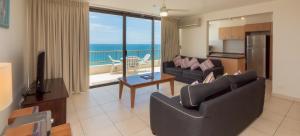 a living room with two couches and a balcony with the ocean at Norfolk Luxury Beachfront Apartments in Gold Coast