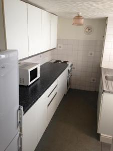 uma pequena cozinha com armários brancos e um micro-ondas em Isambard Cottage em Weymouth
