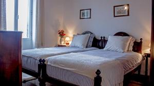 a bedroom with two beds with white blankets and pillows at Vila Joaninha in Santo António da Serra