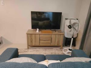 a living room with a blue couch and a tv and a fan at Cozy and Affordable Deluxe Condo near Puerto Princessa Airport in Puerto Princesa City +17 photos