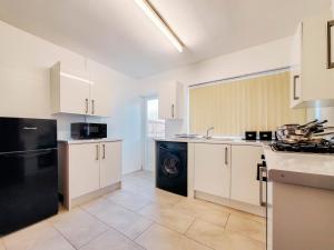 a kitchen with white cabinets and a black dishwasher at Spacious 3 Bedroom Home - Near Nec, Birmingham Airport & Solihull in Birmingham