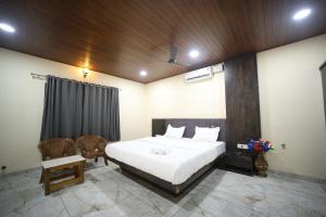 a bedroom with a large white bed and a chair at Aarna Coastal Resort in Māvalli