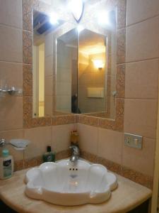 ein Badezimmer mit einem weißen Waschbecken und einem Spiegel in der Unterkunft Apartment Maria in Enna