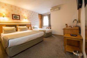 a hotel room with two beds and a desk at Çanak Hotel in Çanakkale