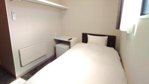 a small room with a bed and a night stand at Ｓｗｉｍｍｙ Ｉｎｎ Ｏｎａｇａｗａ - Vacation STAY 44062v in Onagawa