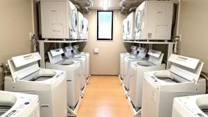 eine Waschküche mit weißen Waschmaschinen und Trocknern auf Regalen in der Unterkunft Ｓｗｉｍｍｙ Ｉｎｎ Ｏｎａｇａｗａ - Vacation STAY 44047v in Onagawa