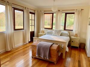 Un dormitorio con una cama en una habitación con ventanas. en Avalon River Retreat - 400 acre off the grid riverside nature & platypus oasis, en Ellenborough