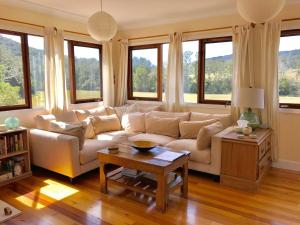 sala de estar con sofá blanco y ventanas en Avalon River Retreat - 400 acre off the grid riverside nature & platypus oasis, en Ellenborough