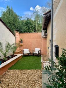 a patio with two chairs and a table and grass at La petite maison in Neuvic +10 photos