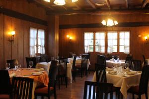 a dining room with tables and chairs and windows at Hotel Molina Real in Molinaseca