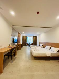 马尼帕尔Richmond Inn and Suites的大房间设有两张床、一张桌子和一台电脑 更多13张照片