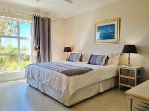 Un dormitorio con una cama grande y una ventana. en 'Goldwater on Beach' - 3 Bedroom Beachfront with Balcony & BBQ - Sleeps 6, en Gordonʼs Bay