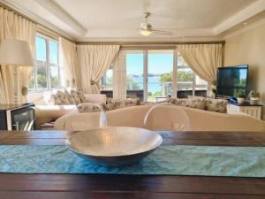 Una sala de estar con un sofá grande y una mesa. en 'Goldwater on Beach' - 3 Bedroom Beachfront with Balcony & BBQ - Sleeps 6, en Gordonʼs Bay