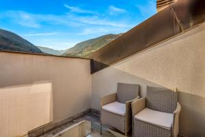 two chairs on a balcony with mountains in the background at Loft&Sun in La Spezia
