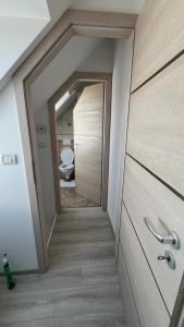 a bathroom with a toilet and a hallway with a door at Muller Premium Suite 12 Iulius Mall in Timişoara