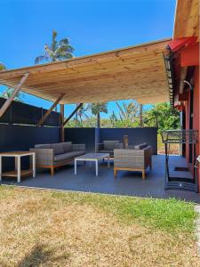 a patio with couches and tables under a wooden pergola at Case Lénora Les Cases de Langevin in Saint-Joseph