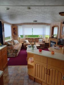 ein Wohnzimmer mit einer Küche und ein Wohnzimmer mit einem Sofa in der Unterkunft chalet 16 de tien heugten drenthe in Schoonloo