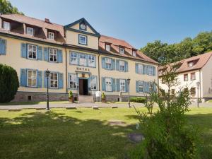 a large yellow building with blue windows on a park at Hotel Zum Herrenhaus in Behringen