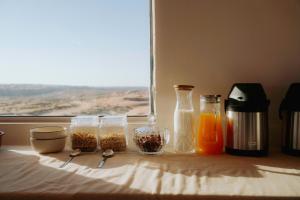 a table with four glass containers of food and a window at Silent Dunes Camp in Ḩawīyah