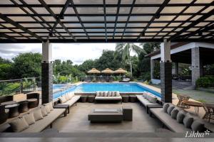 a patio with a pool with couches and chairs at Likha Wellness Resort in Lipa