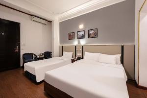 a hotel room with two beds and a desk at A25 Hotel - 80 Mai Hắc Đế in Hanoi +9 photos
